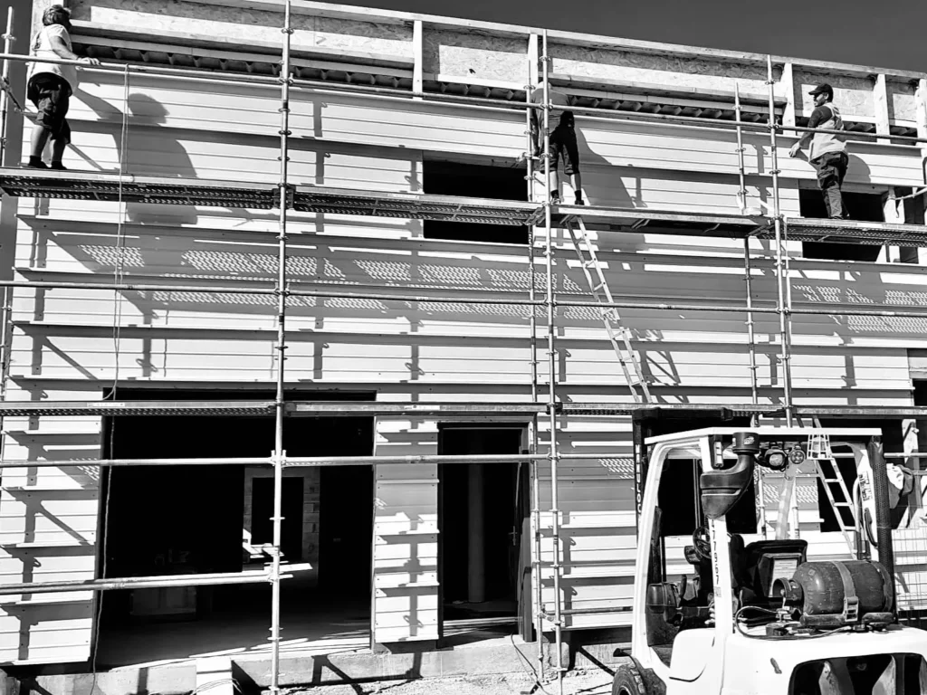 Équipe DEFIS réalisant des travaux de bâtiment traditionnel sur un chantier avec échafaudage.