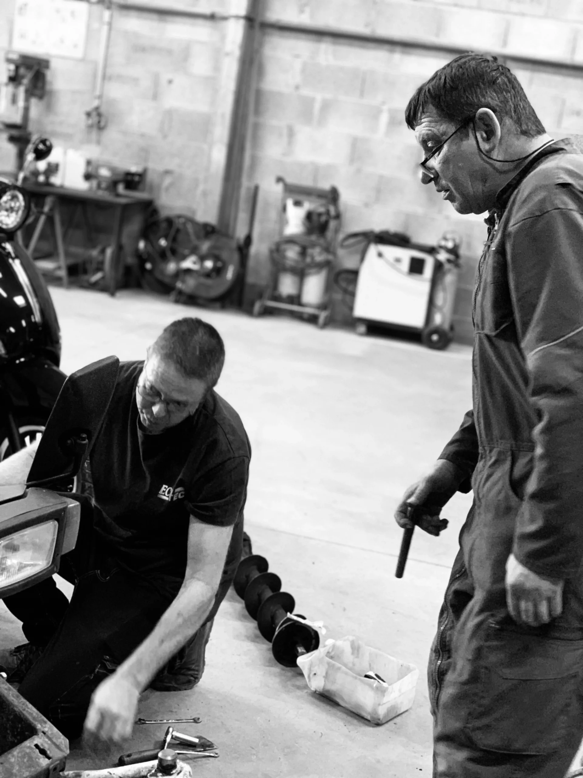 Équipe DEFIS réalisant une intervention mécanique sur un véhicule dans le garage solidaire.